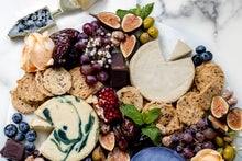 Load image into Gallery viewer, marble cheese board with chocolate, crackers and fruit, seen from above
