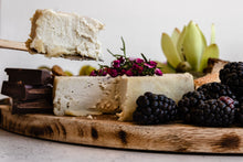 Load image into Gallery viewer, close up of a cheese being cut into, next to berries and chocolate
