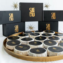 Load image into Gallery viewer, SriMu black and gold boxes with a tray of packaged cheese wheels in front of it
